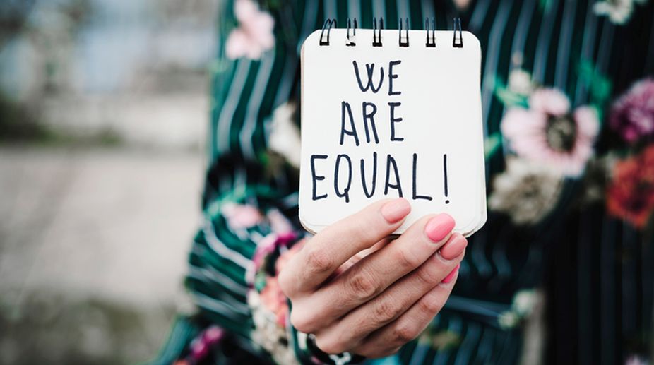 woman shows notepad with the text we are equal